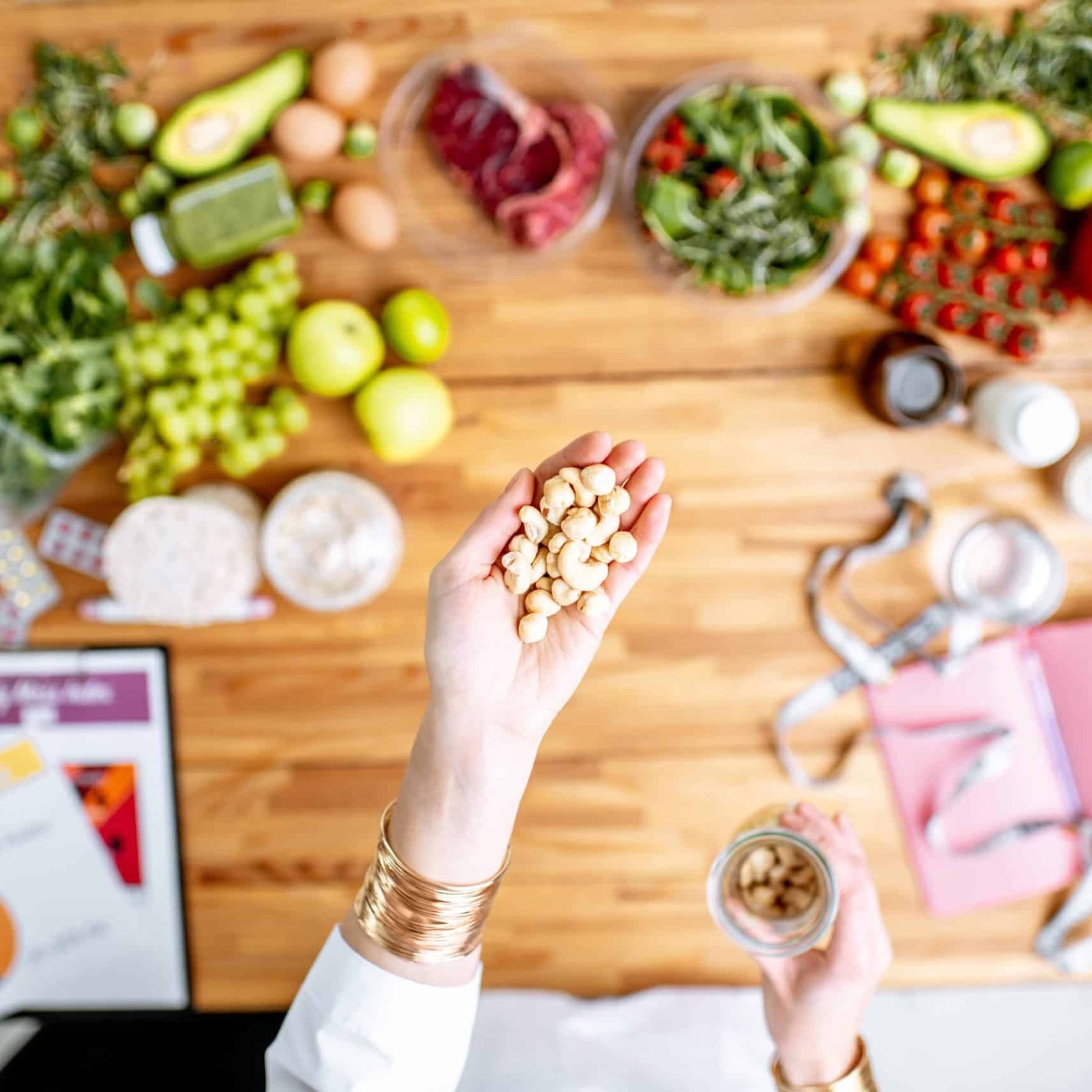 dietitian-holding-nuts-above-the-table-full-of-hea-2023-11-27-04-51-36-utc-min